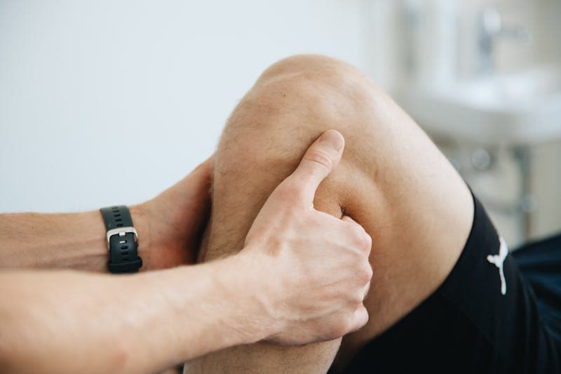 Physical therapist stretching a patient's arm in a bright, sunny treatment room